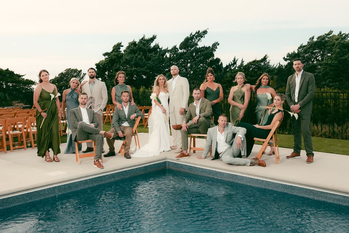The wedding party posing with the couple beside a pool